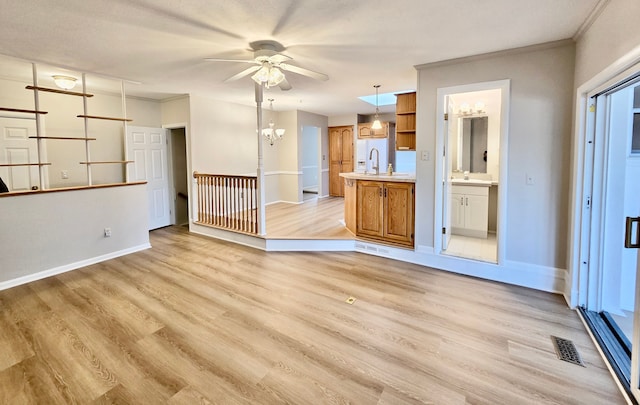 unfurnished living room featuring light wood-type flooring, visible vents, and a sink