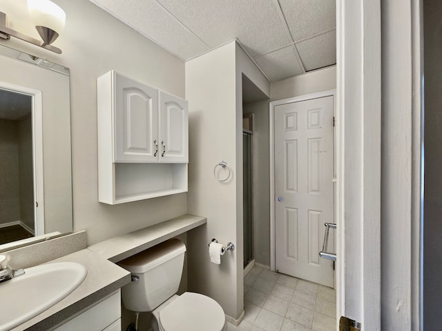 bathroom with vanity, a drop ceiling, a shower stall, tile patterned floors, and toilet