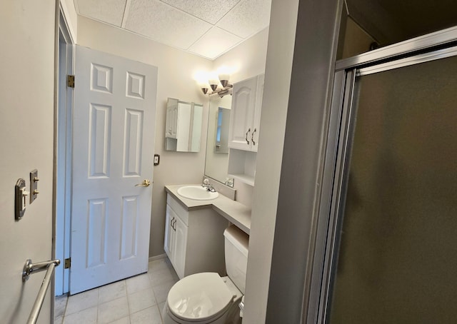 bathroom featuring vanity, a paneled ceiling, tile patterned floors, toilet, and a shower with door