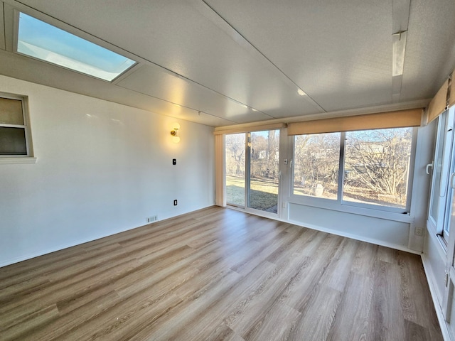 unfurnished sunroom with visible vents and a skylight