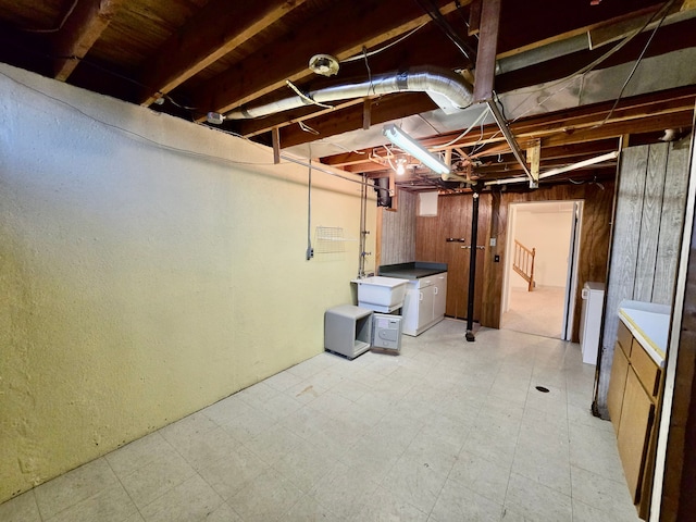 unfinished basement featuring wooden walls and light floors