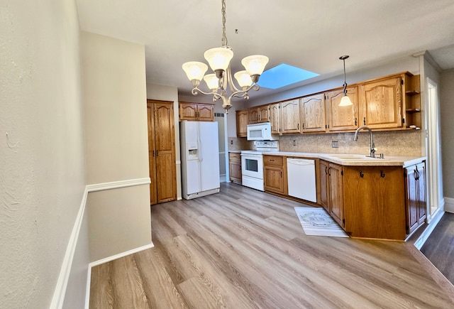 kitchen featuring white appliances, a skylight, light wood-type flooring, and a sink