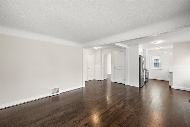 unfurnished living room with a textured ceiling, dark wood finished floors, and visible vents