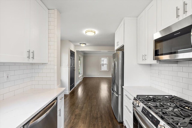 kitchen featuring stainless steel appliances, dark wood-type flooring, white cabinetry, light stone countertops, and baseboards