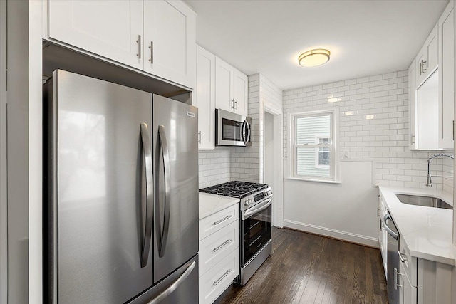 kitchen featuring dark wood-style floors, appliances with stainless steel finishes, a sink, and tasteful backsplash