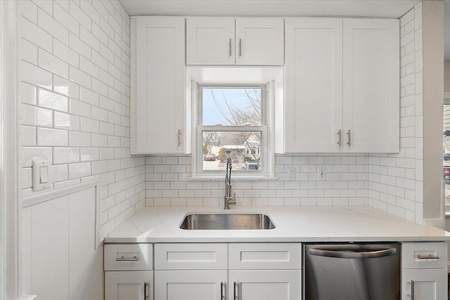 kitchen featuring white cabinets, backsplash, a sink, light stone countertops, and stainless steel dishwasher