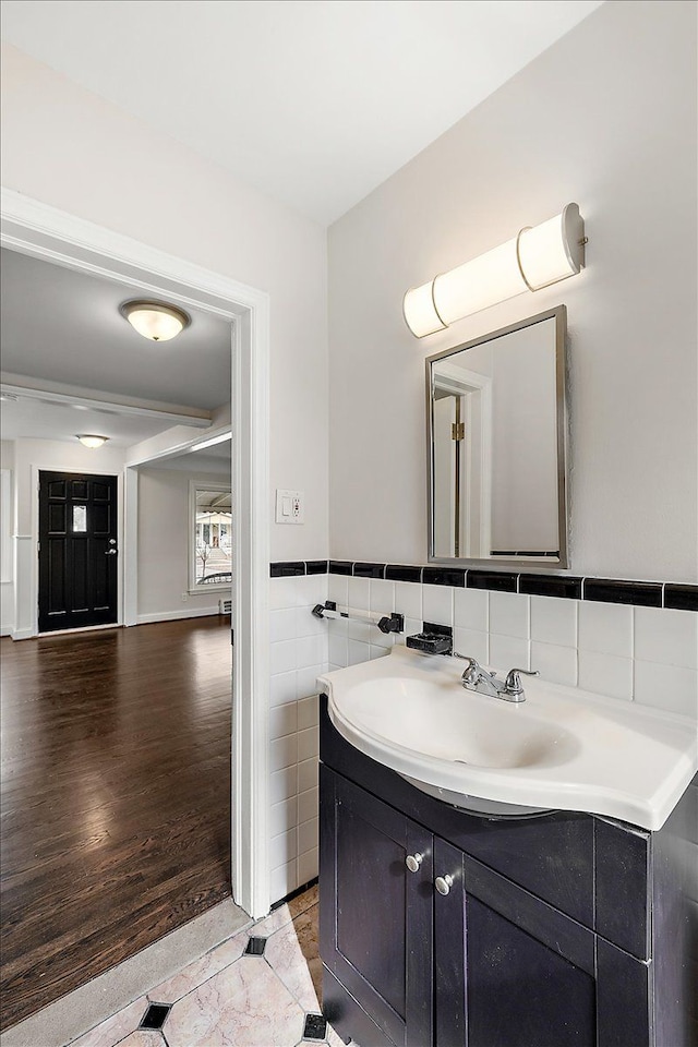 bathroom with a wainscoted wall, tile walls, vanity, and wood finished floors