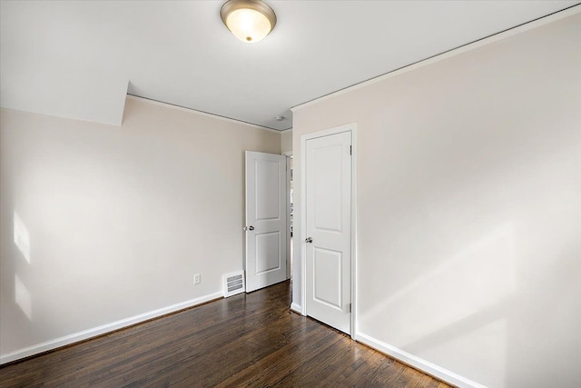 unfurnished room with dark wood-style flooring, visible vents, crown molding, and baseboards