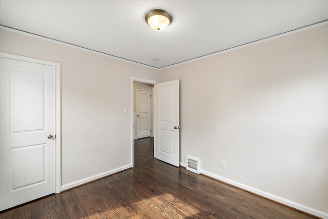 unfurnished bedroom featuring dark wood-style flooring, visible vents, and baseboards