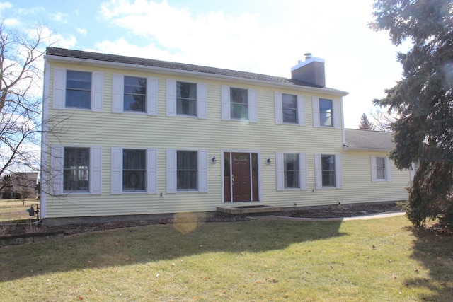 colonial house with a front yard and a chimney