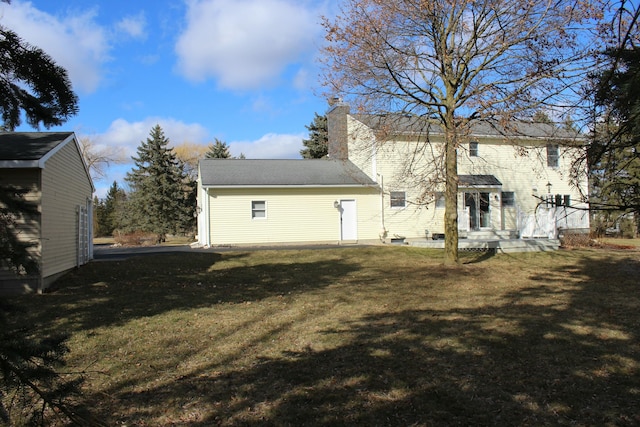 back of house featuring a yard and a chimney