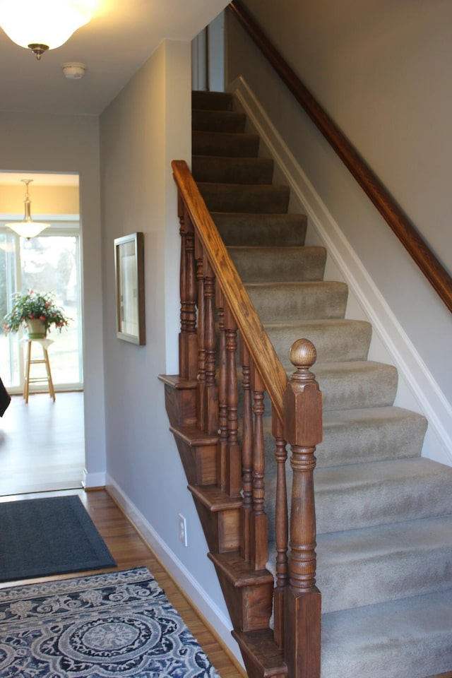 staircase with baseboards and wood finished floors