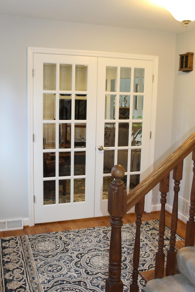 doorway with wood finished floors, visible vents, baseboards, stairs, and french doors