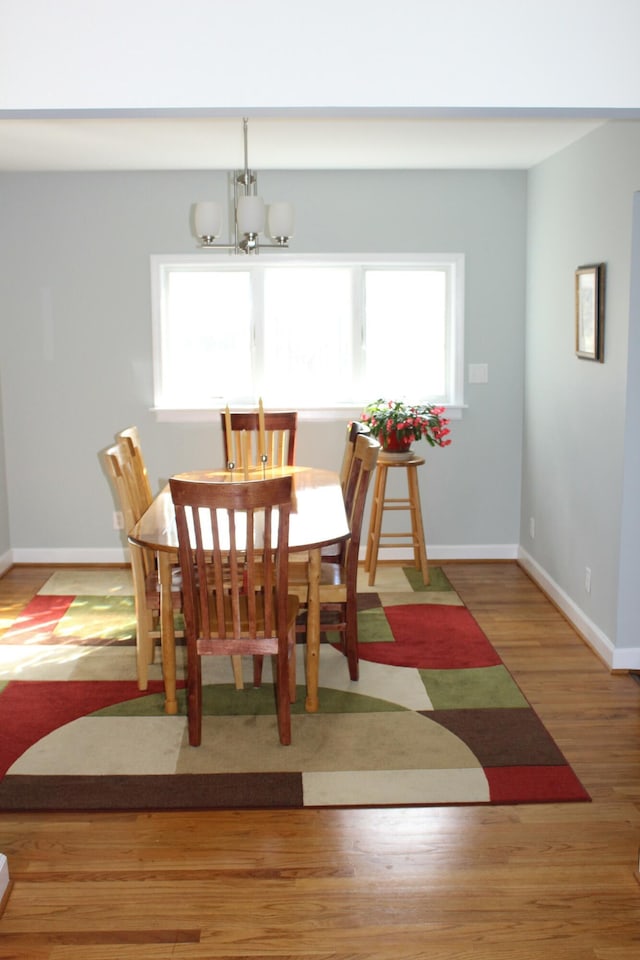 dining space with plenty of natural light, wood finished floors, baseboards, and a chandelier