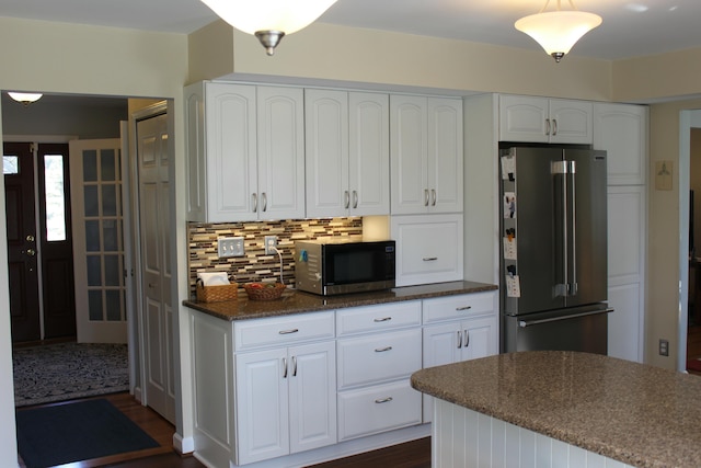 kitchen featuring decorative backsplash, high end fridge, white cabinetry, and dark stone countertops