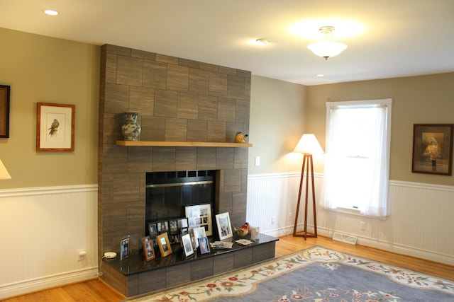 living area featuring recessed lighting, wood finished floors, wainscoting, and a tiled fireplace