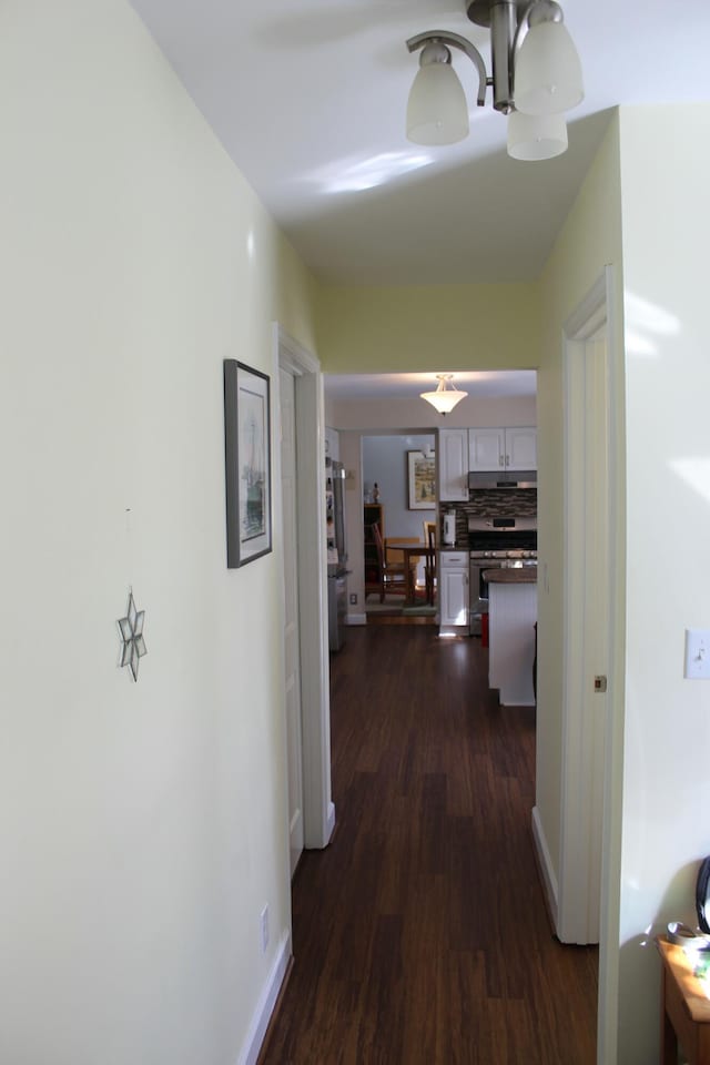 hallway with dark wood-style floors and baseboards