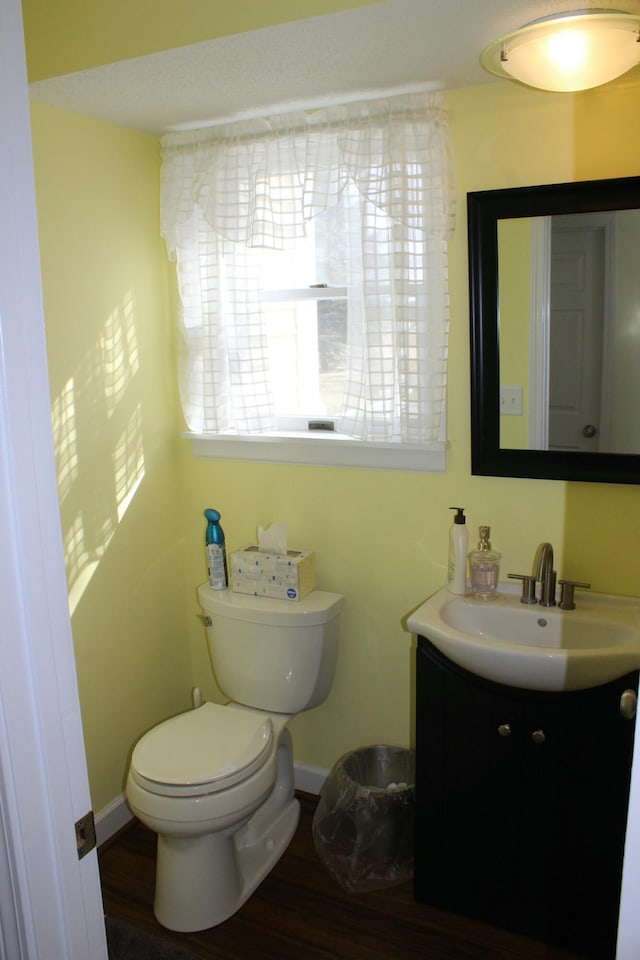 bathroom with vanity, toilet, wood finished floors, and baseboards