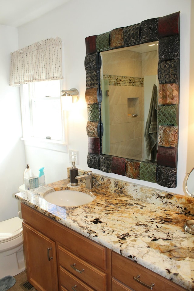 bathroom featuring visible vents, tiled shower, toilet, and vanity