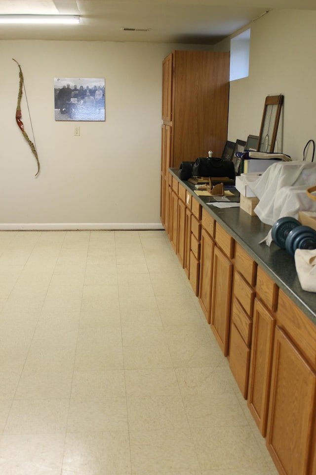 kitchen with dark countertops, visible vents, brown cabinets, and baseboards