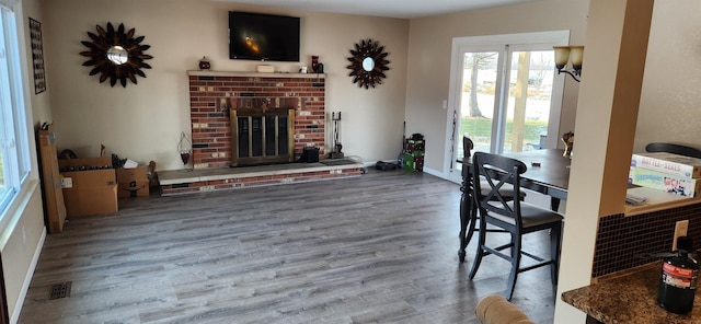 dining space featuring a brick fireplace, wood finished floors, and visible vents