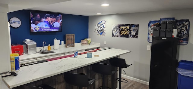 bar featuring recessed lighting, baseboards, a sink, and wood finished floors