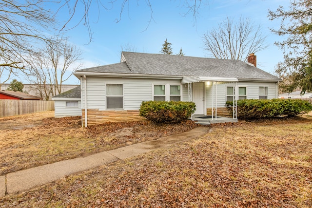 view of front of home with stone siding, a chimney, fence, and roof with shingles