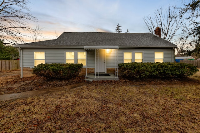 single story home featuring a chimney, fence, and roof with shingles