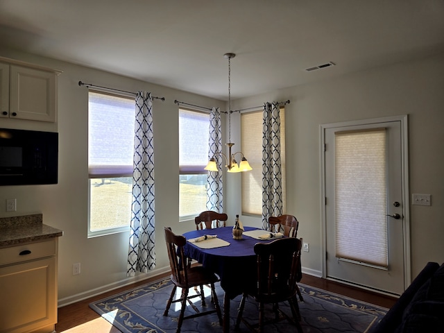 dining space featuring baseboards, visible vents, a chandelier, and dark wood-type flooring