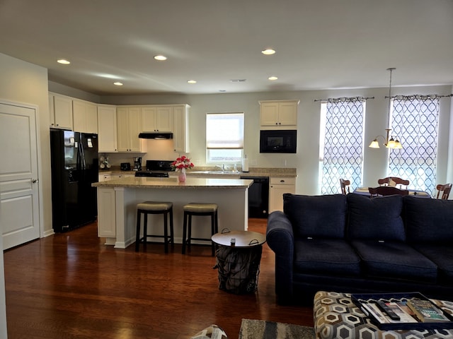 living area featuring a chandelier, dark wood-type flooring, and recessed lighting