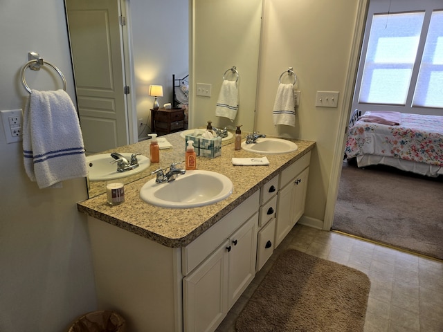 ensuite bathroom with double vanity, ensuite bath, and a sink