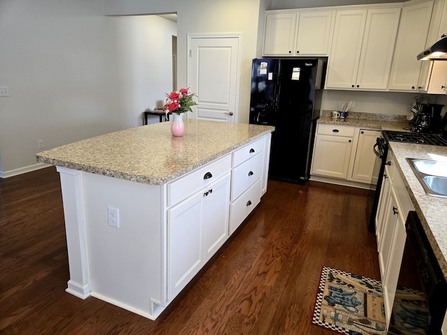 kitchen featuring white cabinets, light stone counters, dark wood-type flooring, a center island, and black appliances