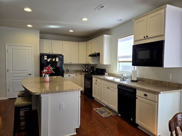 kitchen featuring dark wood-style flooring, under cabinet range hood, black appliances, a sink, and recessed lighting