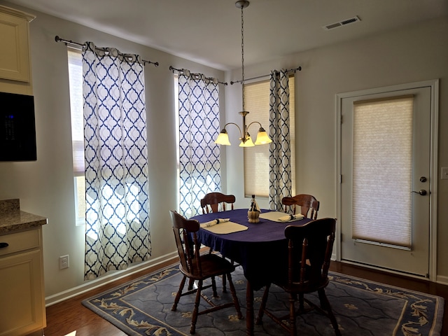 dining room featuring a chandelier, dark wood-type flooring, visible vents, and baseboards