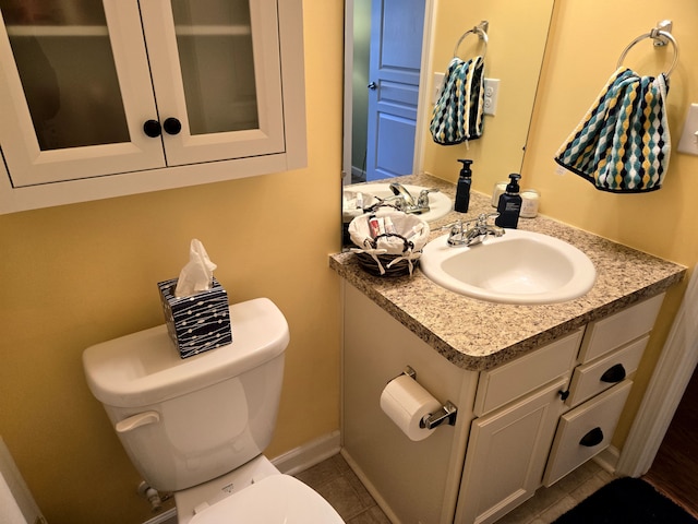 half bathroom with tile patterned floors, vanity, toilet, and baseboards