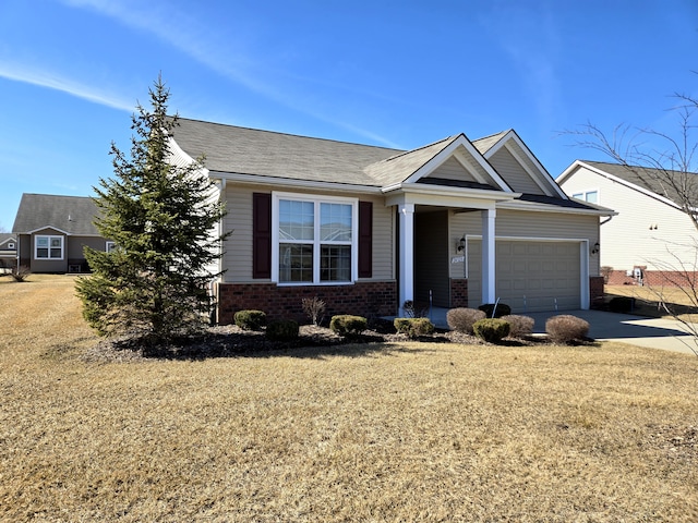 craftsman-style home featuring a front yard, concrete driveway, brick siding, and an attached garage