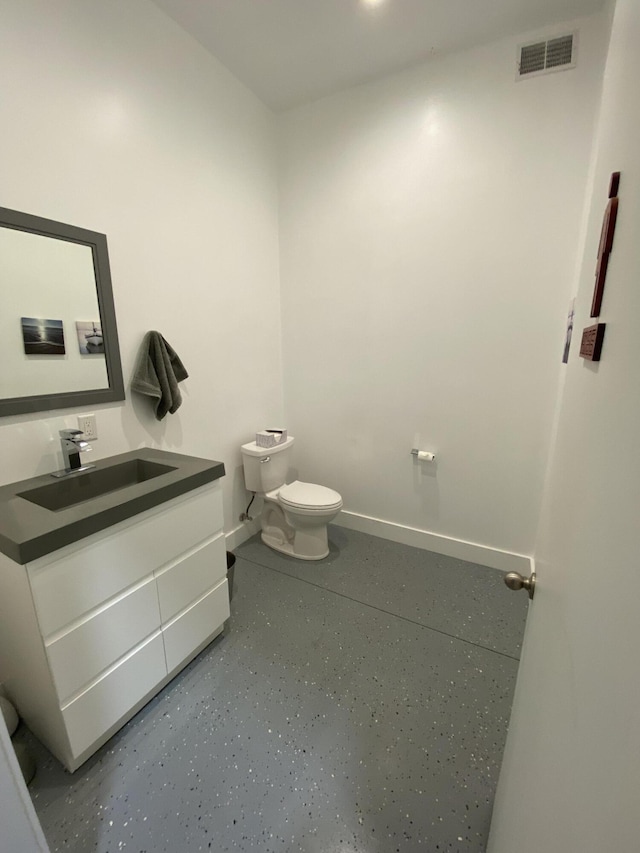 half bathroom with visible vents, toilet, vanity, and baseboards