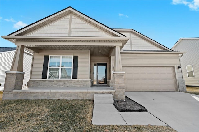 view of front of home featuring stone siding, covered porch, driveway, and a garage