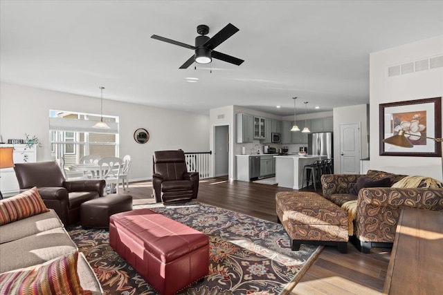 living room with visible vents, dark wood-type flooring, and a ceiling fan