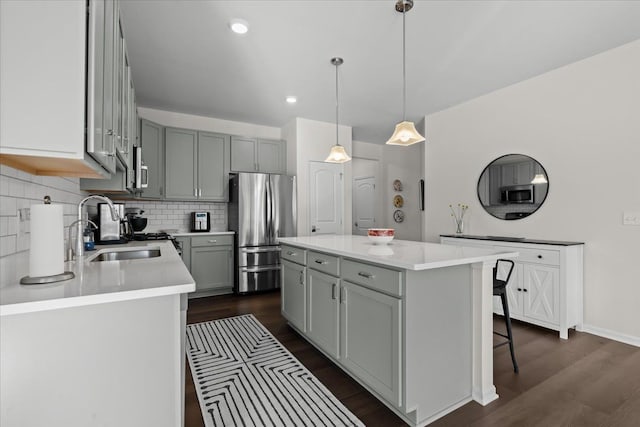 kitchen featuring decorative backsplash, dark wood finished floors, appliances with stainless steel finishes, and a sink