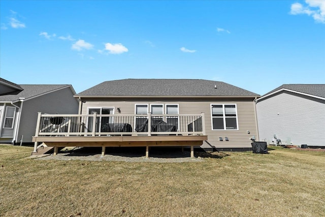 rear view of property with a lawn, roof with shingles, and a wooden deck