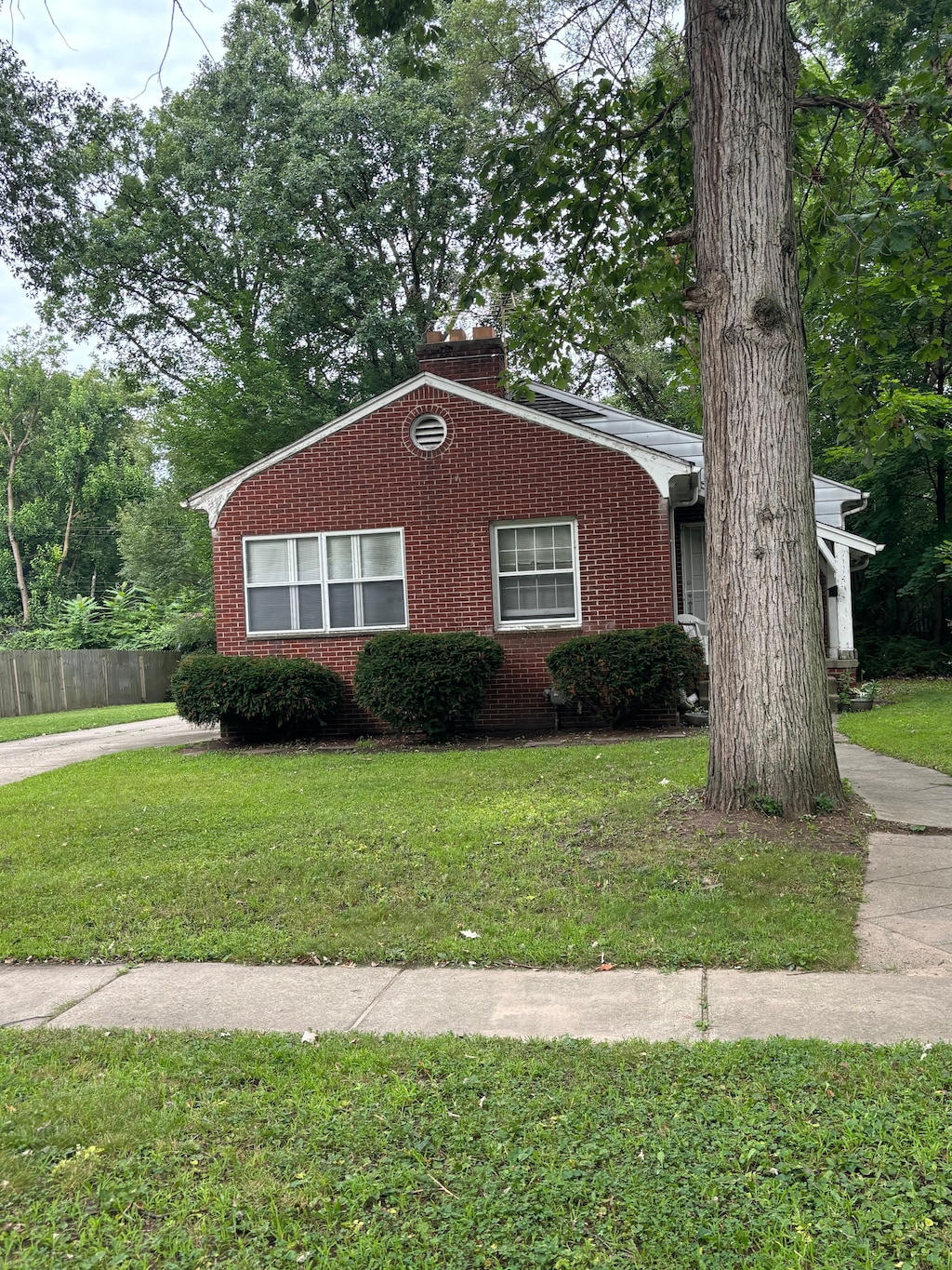 view of front facade featuring brick siding, a front lawn, and fence