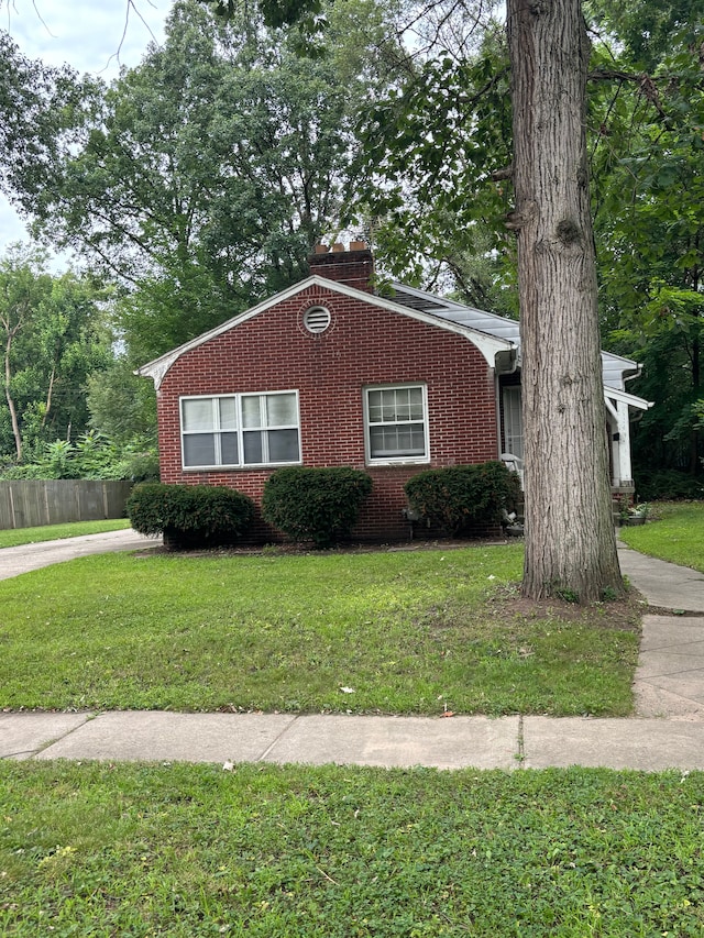 view of front facade featuring brick siding, a front lawn, and fence