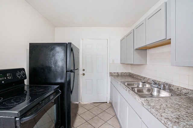 kitchen with light tile patterned floors, a sink, light countertops, backsplash, and black appliances