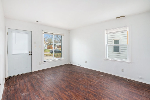 unfurnished room featuring wood finished floors, visible vents, and baseboards