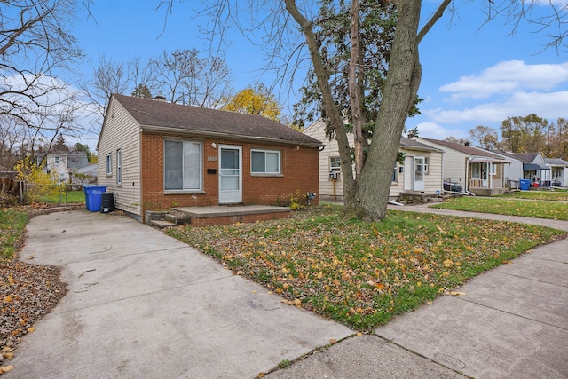 bungalow with a residential view, a chimney, fence, a front lawn, and brick siding