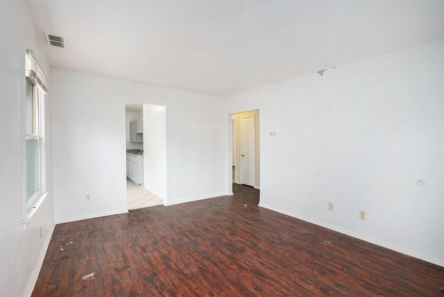 empty room featuring visible vents, baseboards, and wood finished floors