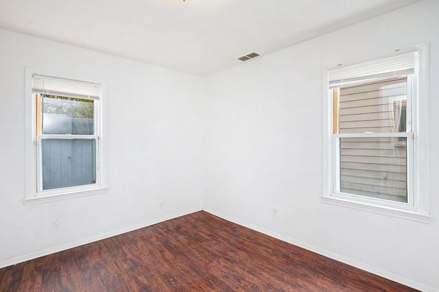 empty room featuring baseboards, visible vents, and dark wood-type flooring