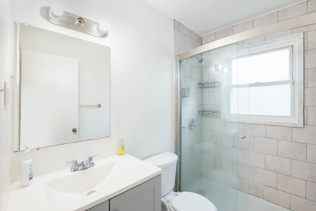 full bath with tiled shower, vanity, and toilet