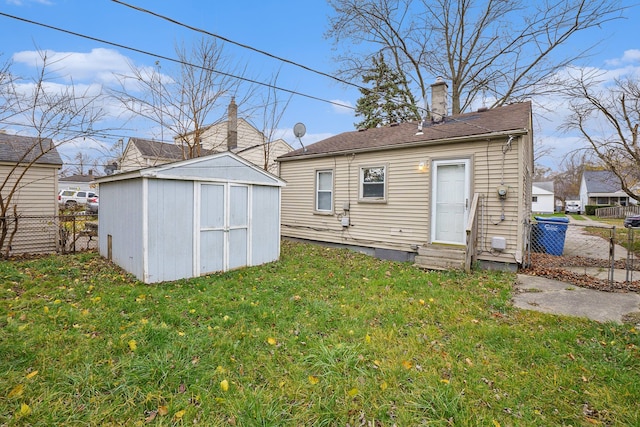 back of property featuring entry steps, a yard, a storage unit, and fence